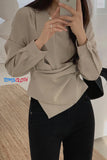 Person wearing a beige blouse and black pants, holding a phone with 'TOMS CLOTH' branding.