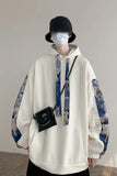 Person wearing a white hoodie with blue patterned sleeves and a black bucket hat.