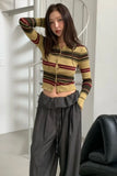 Person wearing a striped cardigan and gray pants in an indoor setting