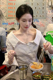 Woman eating at a restaurant with various dishes and drinks on the table.