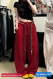 Person wearing red pants with a chain detail in a clothing store.