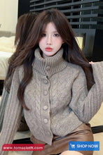 Woman wearing a gray cable knit sweater with a blurred background