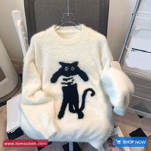 White fluffy sweater with black cat design on a hanger, brand 'Toms Cloth' visible.