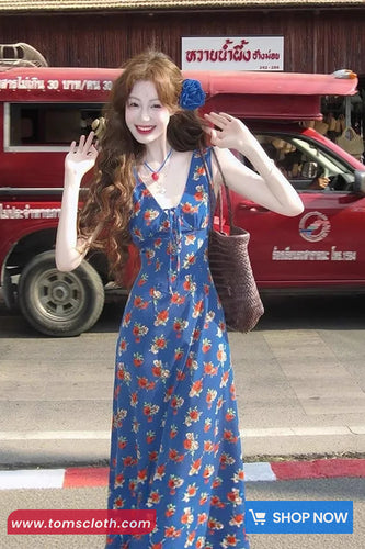 Woman in a blue floral dress posing in front of a red vehicle with text on the roof.