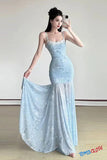 Woman in a light blue lace dress holding the train of the dress indoors.