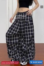 Person wearing black and white checkered pants with text, standing against a white wall.