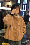 Person wearing a beige jacket with a blurred indoor background