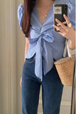 Person wearing a blue checkered blouse with a bow and blue jeans, holding a phone and basket.
