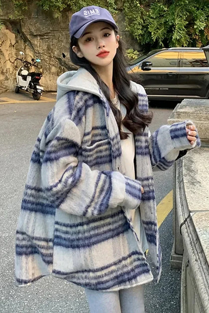Woman wearing a blue and white striped coat with a hood, standing on a street.