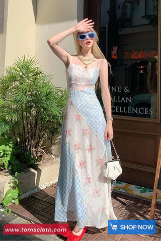 Woman in a floral dress standing outdoors with a store in the background