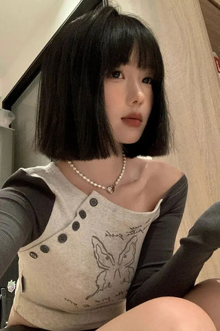 Person wearing a beige top with butterfly design and gray sleeves.