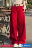 Person wearing red pants and a white shirt in an outdoor setting with tables and chairs.