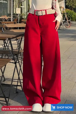Person wearing red pants and a white shirt in an outdoor setting with tables and chairs.