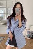 Person wearing a blue and white striped shirt taking a mirror selfie indoors.