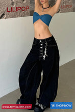 Person wearing a blue top and black high-waisted pants with buttons, standing against a plain background.