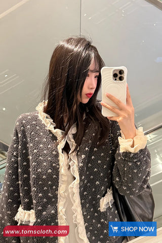 Woman taking a mirror selfie wearing a textured jacket with lace details, holding a phone.