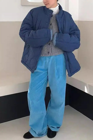 Person wearing a blue puffer jacket and pants in a minimal indoor setting