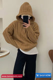 Person wearing a brown cable knit hoodie taking a mirror selfie.