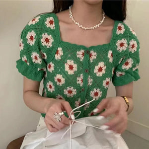 Person wearing a green floral-patterned top with a plain background