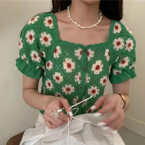 Person wearing a green floral-patterned top with a plain background