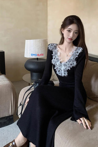 Woman in a black dress with lace details sitting on a couch.