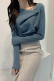 Person wearing a blue sweater and gray pants against a white background