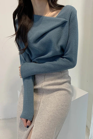 Person wearing a blue sweater and gray pants against a white background