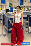 Woman wearing a white top and red plaid pants in a store setting with promotional text at the bottom.