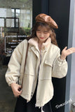 Woman wearing a beige jacket and beret standing outside a store with store hours displayed.