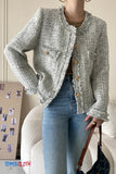 Person wearing a textured gray jacket with gold buttons and blue jeans, holding a handbag.