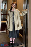 Person wearing a beige coat in an elevator, with 'Toms Cloth' branding visible.