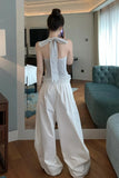 Woman in a white outfit taking a mirror selfie in a modern living room.