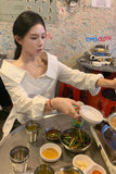 Woman serving food at a dining table with various dishes and drinks.