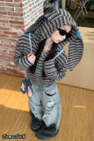 Person wearing a textured gray hooded jacket in an indoor setting.