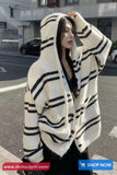 Person wearing a white and black striped sweater on a street.