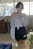 Person taking a mirror selfie wearing a striped shirt and black shorts in a room with furniture and decor.