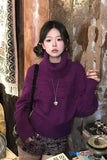 Person wearing a purple sweater in an indoor setting with decorative elements.