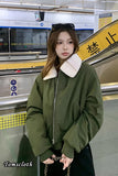 Person wearing a green jacket with a white collar in a subway station, with 'Tomscloth' branding.