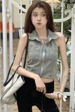 Woman wearing a denim vest and black pants holding a beige bag.