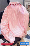 Pink striped shirt on a mannequin with a magazine in the background