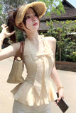 Woman in a beige dress and straw hat posing outdoors.