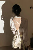 Person wearing a white lace top and striped shorts with a blurred background