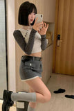 Person taking a mirror selfie wearing a gray long-sleeve top and shorts indoors.