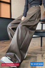 Person wearing brown leather pants sitting on a chair indoors.