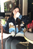 Person wearing a cozy sweater with a winter scene design, sitting indoors.