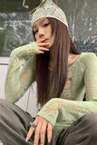 Person wearing a textured green sweater and hat, sitting against a plain background