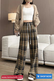 Person wearing a beige cardigan, white top, and plaid pants in a living room setting.