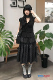 Woman in a black outfit with polka dot patterns in an indoor setting.