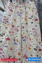 Floral patterned pants hanging on a rack with 'TomsCloth.com' branding.