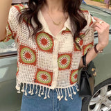 Person wearing a colorful crochet cardigan with geometric patterns, standing next to a car.